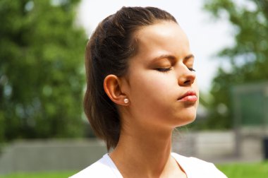 Genç güzel kadın parkta meditasyon yapıyor.