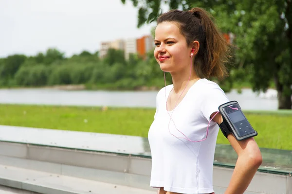 Jogging girl in the city listing music by headphones
