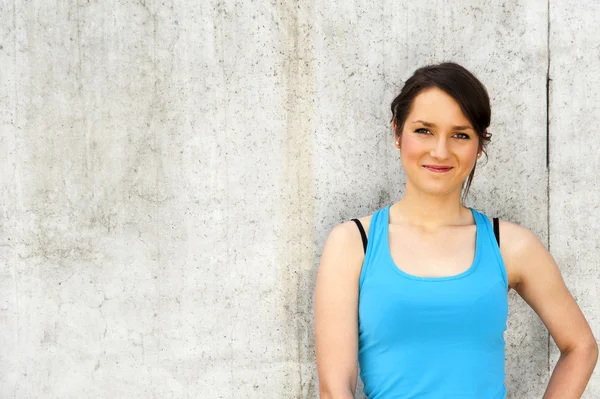 Young woman resting after run by the wall in city with big smile — Stock Photo, Image