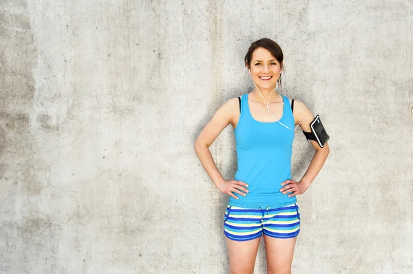 Young woman resting after run by the wall in city with big smile — Stock Photo, Image