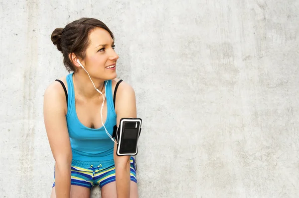 Joven mujer descansando después de correr por la pared en la ciudad con una gran sonrisa — Foto de Stock