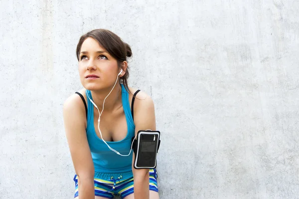 Joven mujer descansando después de correr por la pared en la ciudad con una gran sonrisa — Foto de Stock