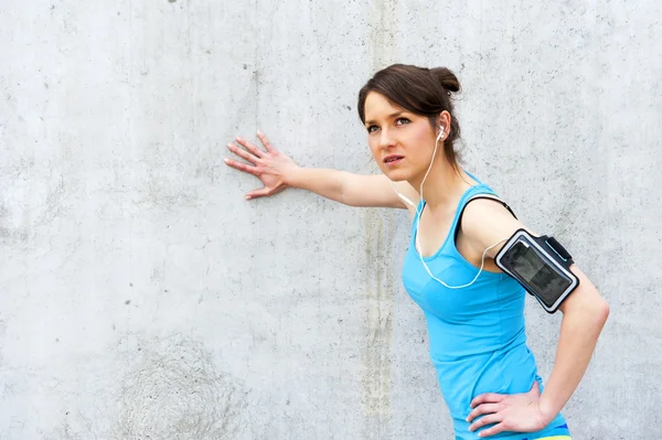 Young woman resting after run by the wall in city with big smile — Stock Photo, Image