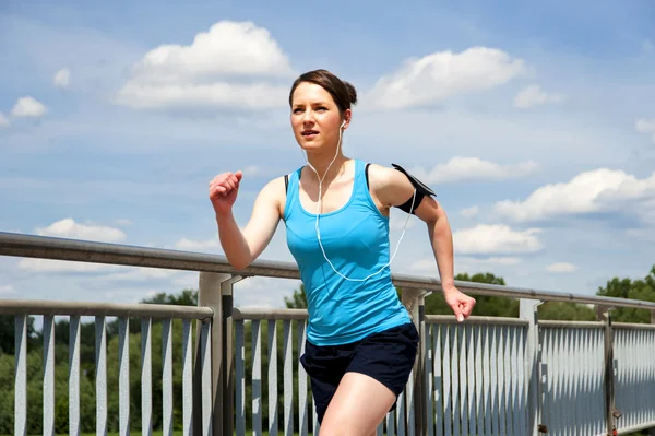 Young girl running in teh city, over the river by the bridge — Stock Photo, Image