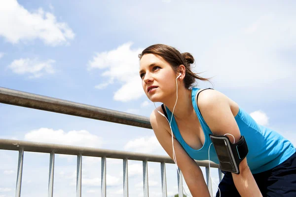 genç kadın çalıştırdıktan sonra dinlenme. Mavi spor içinde. üzerinde gökyüzü