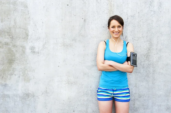 Young woman resting after run by the wall in city with big smile — Stock Photo, Image