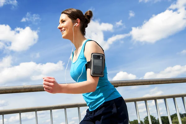 Jonge vrouw runing in de stad over de brige in zonlicht, smil — Stockfoto