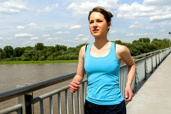 Jonge vrouw runing in de stad over de brige in zonlicht, smil — Stockfoto