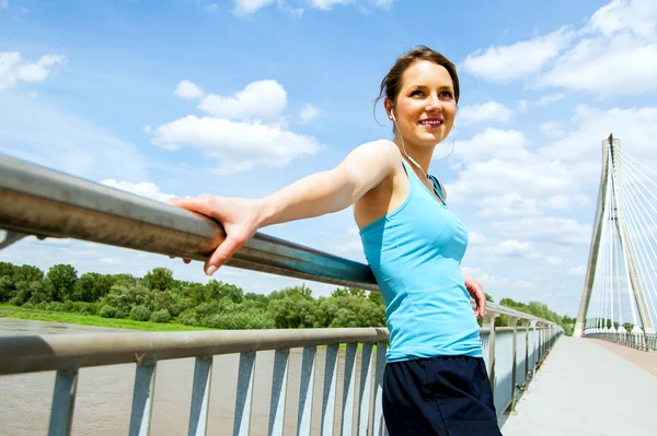 Young moe vrouw rest nadat lopen in de stad over de brug. — Stockfoto