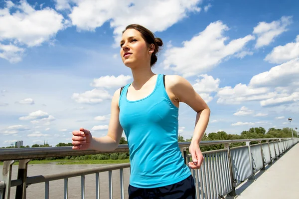 Giovane donna che corre in città oltre il ponte alla luce del sole . — Foto Stock