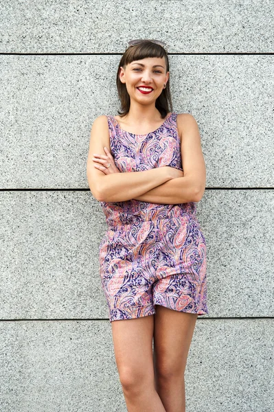 Jovem mulher moderna contra a parede da cidade sorrindo para camer — Fotografia de Stock