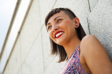 Duvar gülümseyen karşı duran genç modern kadın. Kırmızı dudaklar bir