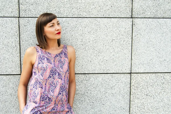 Young modern woman against the wall in the city smiling to camer — Stock Photo, Image