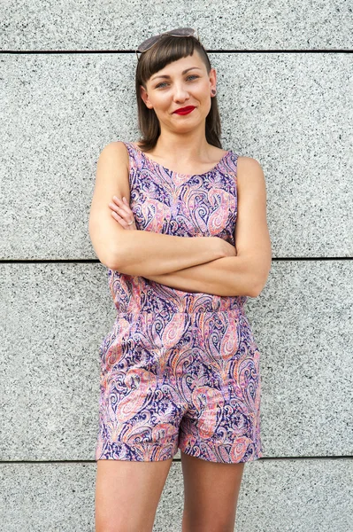 Mladá moderní žena proti zdi v městě s úsměvem camer — Stock fotografie