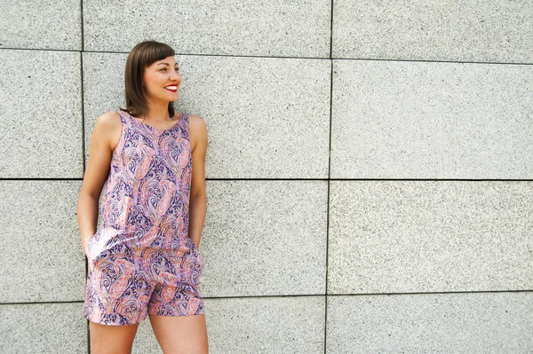 Giovane donna moderna contro il muro della città sorridente a venire — Foto Stock