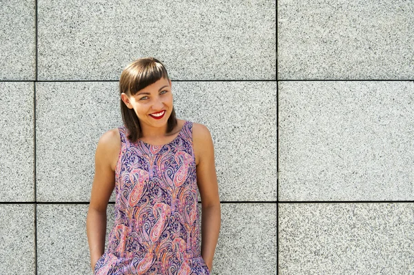 Junge moderne Frau an der Wand in der Stadt lächelt vor den Kameras — Stockfoto