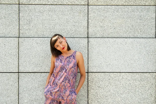 Young modern woman against the wall in the city smiling to camer — Stock Photo, Image