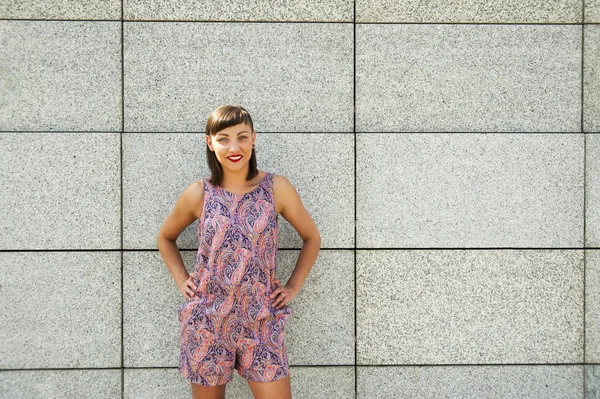 Mladá moderní žena proti zdi v městě s úsměvem camer — Stock fotografie