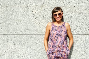 Duvarın içinde şehir gülümseyen güneş gözlüklü genç modern kadın 