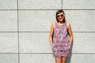 Duvarın içinde şehir gülümseyen güneş gözlüklü genç modern kadın 