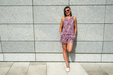 Duvarın içinde şehir gülümseyen güneş gözlüklü genç modern kadın 