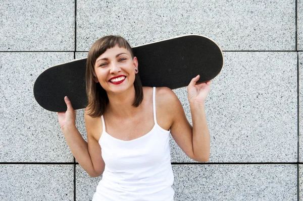 Young girl with skateboard on her shoulders in the city by the w — Stock Photo, Image
