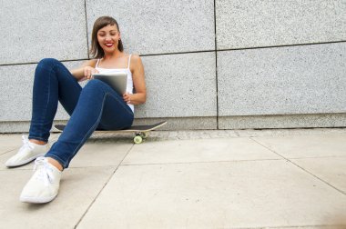 Genç kız tarafından w tablet ile şehirde kaykay üzerinde siting