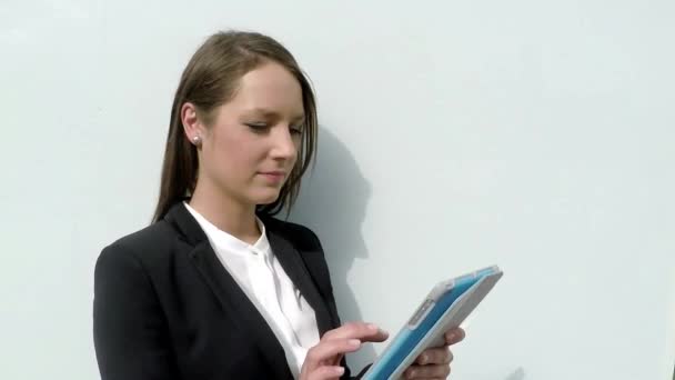 Mujer de negocios navegando por Internet en la tableta contra la pared blanca en la ciudad . — Vídeos de Stock