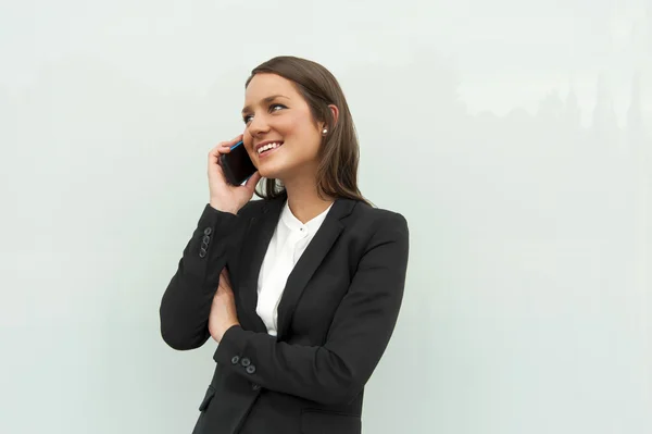 Mujer de negocios hablando por teléfono contra la pared de cristal en la ci — Foto de Stock