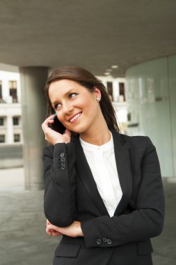 CI cam duvara karşı telefonla konuşurken iş kadını