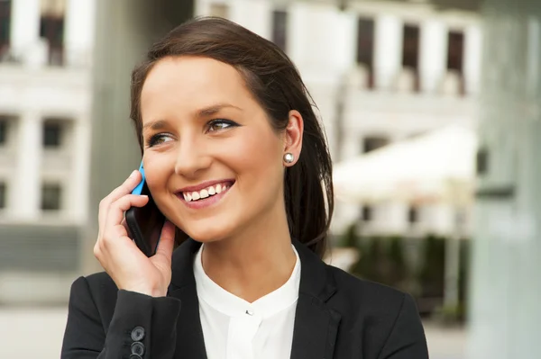 Femme d'affaires parlant par téléphone contre le mur de verre dans le ci — Photo