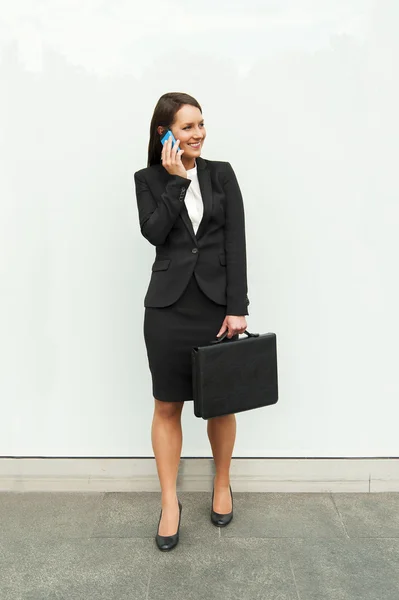 Femme d'affaires debout près du mur de verre blanc dans la ville avec — Photo