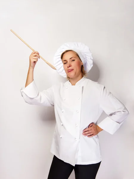 Kvinnan kock håller en sked och provsmakning från sked. På vit baksida — Stockfoto