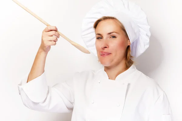 Mulher chef segurando uma colher e degustação de colher. Na parte traseira branca — Fotografia de Stock