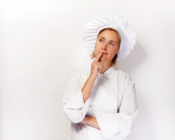 Женщина шеф-повар смотрит вверх и думает пальцем в лицо, над — стоковое фото