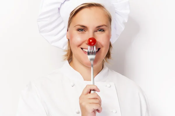 Chef mulher segurar um garfo com tomate contra o nariz, de pé — Fotografia de Stock