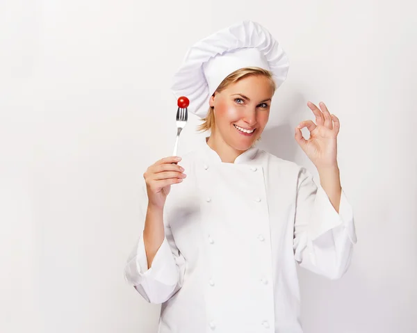 Donna chef che mostra un segno perfetto, con pomodoro sulla forchetta, oltre whi — Foto Stock