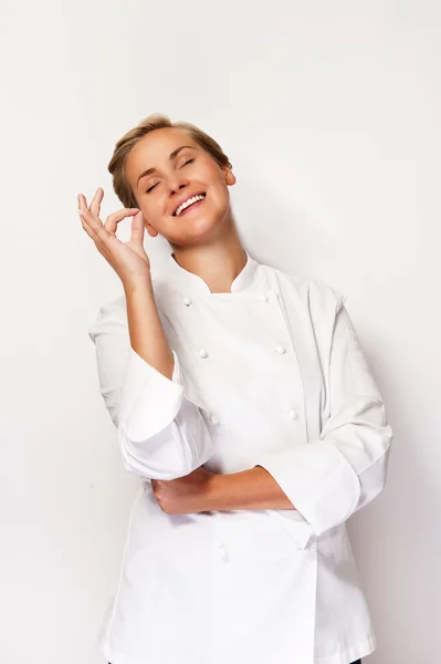 Женщина шеф-повар показывает знак совершенной руки, на белом фоне смайлик — стоковое фото