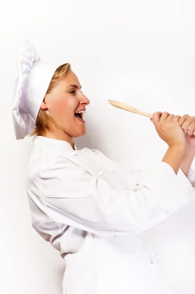 Mulher chef segurando uma colher e degustação de colher. Na parte traseira branca — Fotografia de Stock