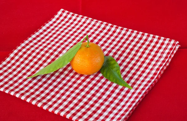 Narancs-mandarin a piros szalvétát — Stock Fotó