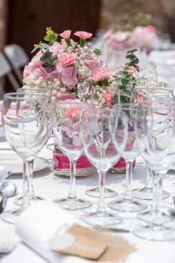 Bir buket pembe çiçek ve şarap kadehiyle süslenmiş düğün masası..