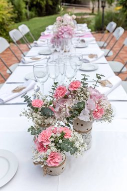 Düğün masası pembe çiçekler ve şarap kadehleriyle süslenmiş..