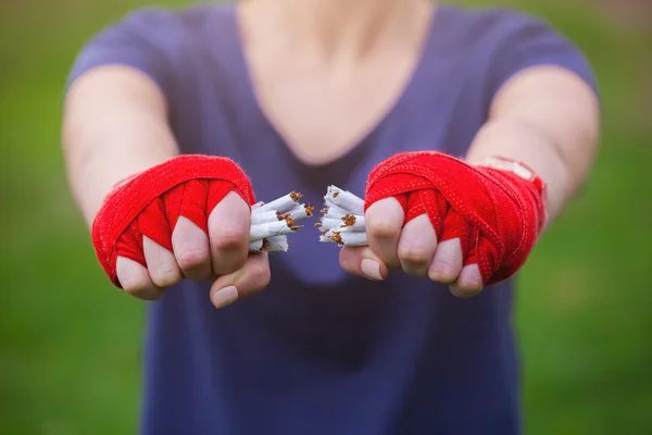 Las chicas de las manos enrolladas en vendas de boxeo rompen una pila de cigare — Foto de Stock