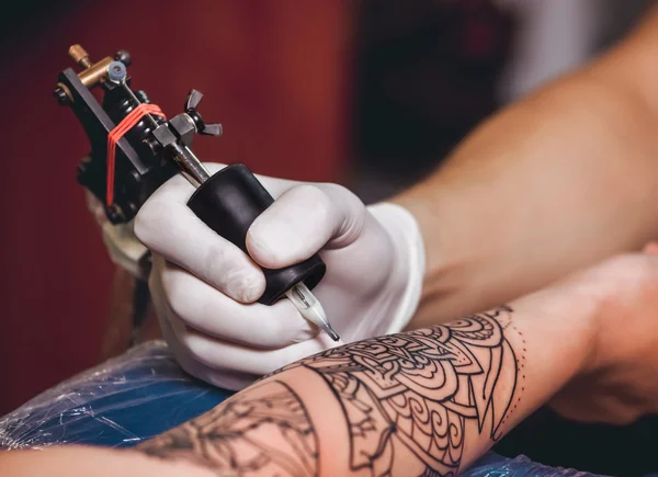 Tattoo master protective gloves make a tattoo in black ink on  the hand of the girl. Close-up — Stock Photo, Image