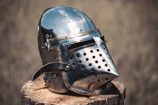 Knight, a brilliant helmet standing on a wooden stump. Close-up.