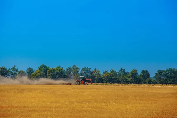 Tracteur de jour d'été tire une charrue sur le champ en pente de blé. Préparation des terres avant plantation . — Photo
