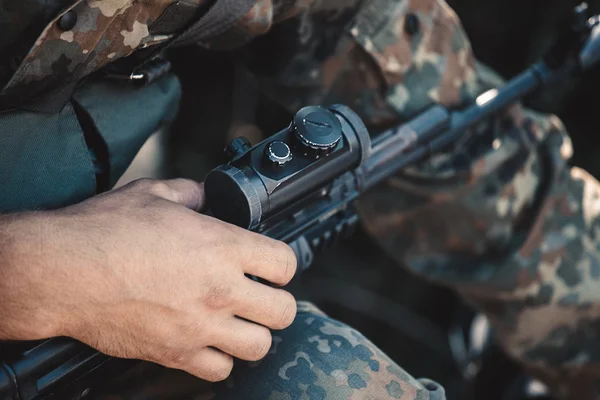 Un soldado ajusta la vista óptica de un rifle . — Foto de Stock