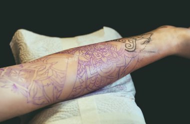 Dövme ustası koruyucu eldivenler kızın eline siyah mürekkeple dövme yapıyor..