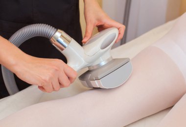 Masör hastanın bacaklarına beyaz bir takım elbiseyle masaj yapıyor. Güzellik salonuna yakın çekim yapıyor..