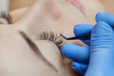 Kirpik uzatma prosedürünü kapat. Güzellik salonunda uzun kirpikleri olan güzel bir kadın.